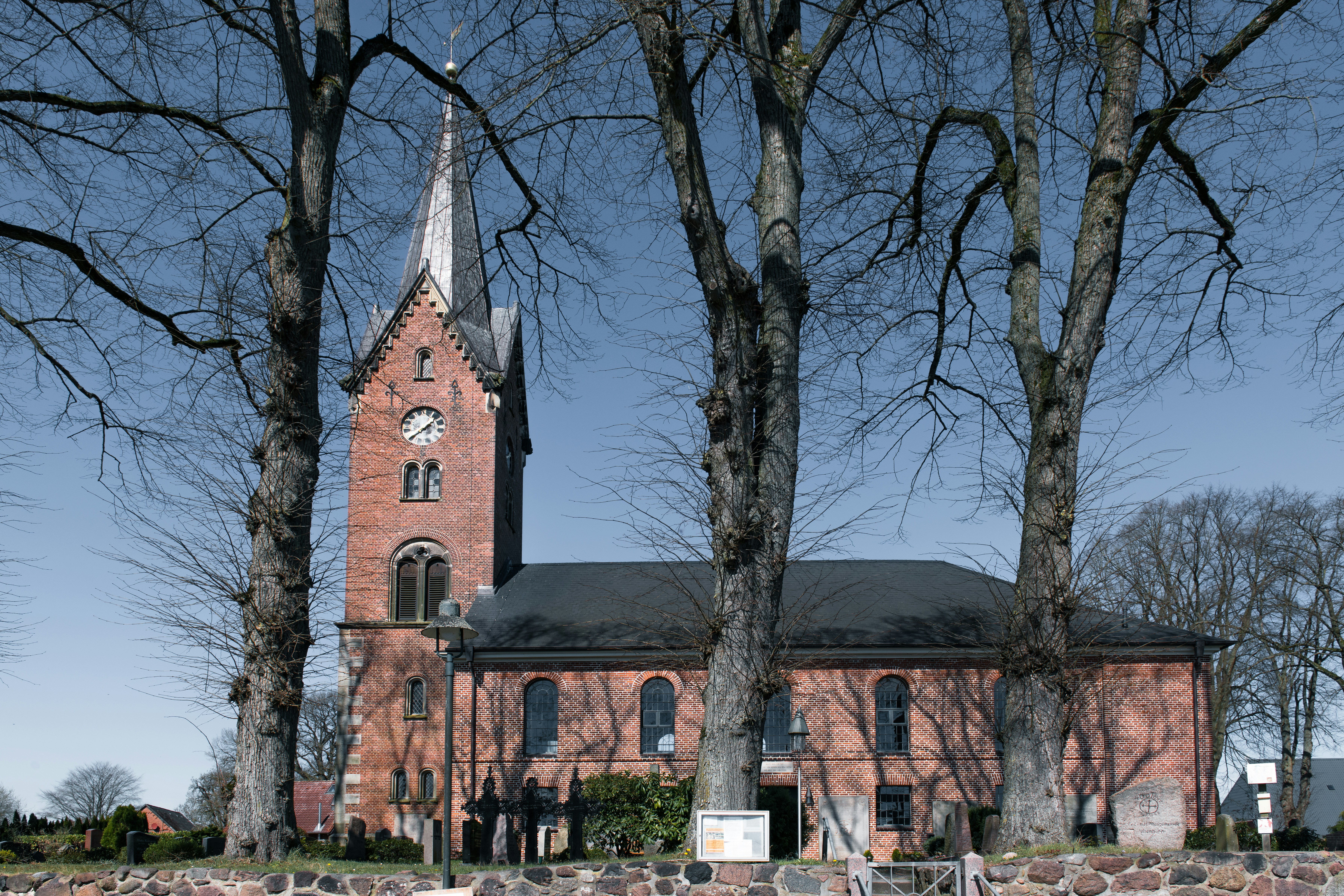 Brick church with tall steeple and bare trees